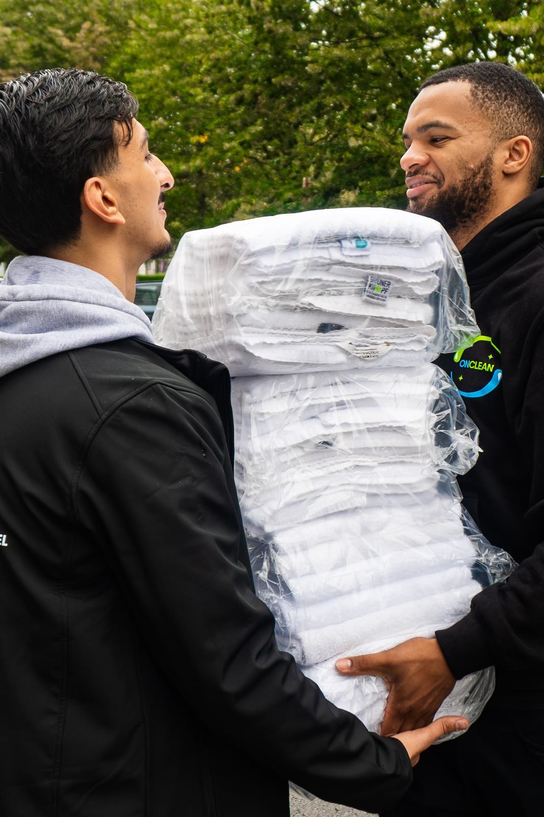 Deux membres de l'équipe OnClean portant des piles de linge emballé